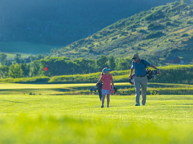 Man and child talking on the golf course